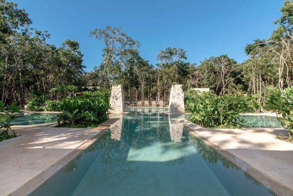 Surrounded by lush greenery, this serene pool area offers a tranquil escape.