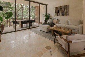 Relax in this spacious living area with a sliding glass door leading to a balcony overlooking lush greenery.
