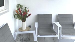 A modern lounge area with two grey lounge chairs, a white sofa, and a decorative wall art of sea turtles. - L'oiseau du Paradis, Charmant T2 Avec vue Imprenable (Les Trois-Îlets)