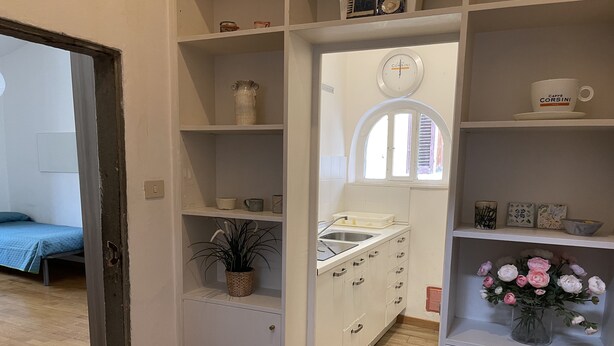 A compact kitchen with white cabinets, a sink, and a window with a view.