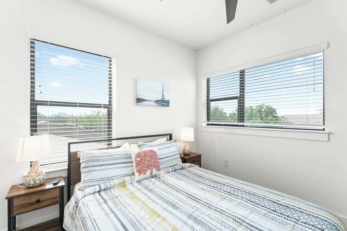 A bedroom with a bed, two nightstands, a lamp, and a picture of the Eiffel Tower.