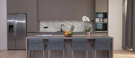 A modern kitchen with a marble backsplash, stainless steel appliances, and a central island with bar stools.