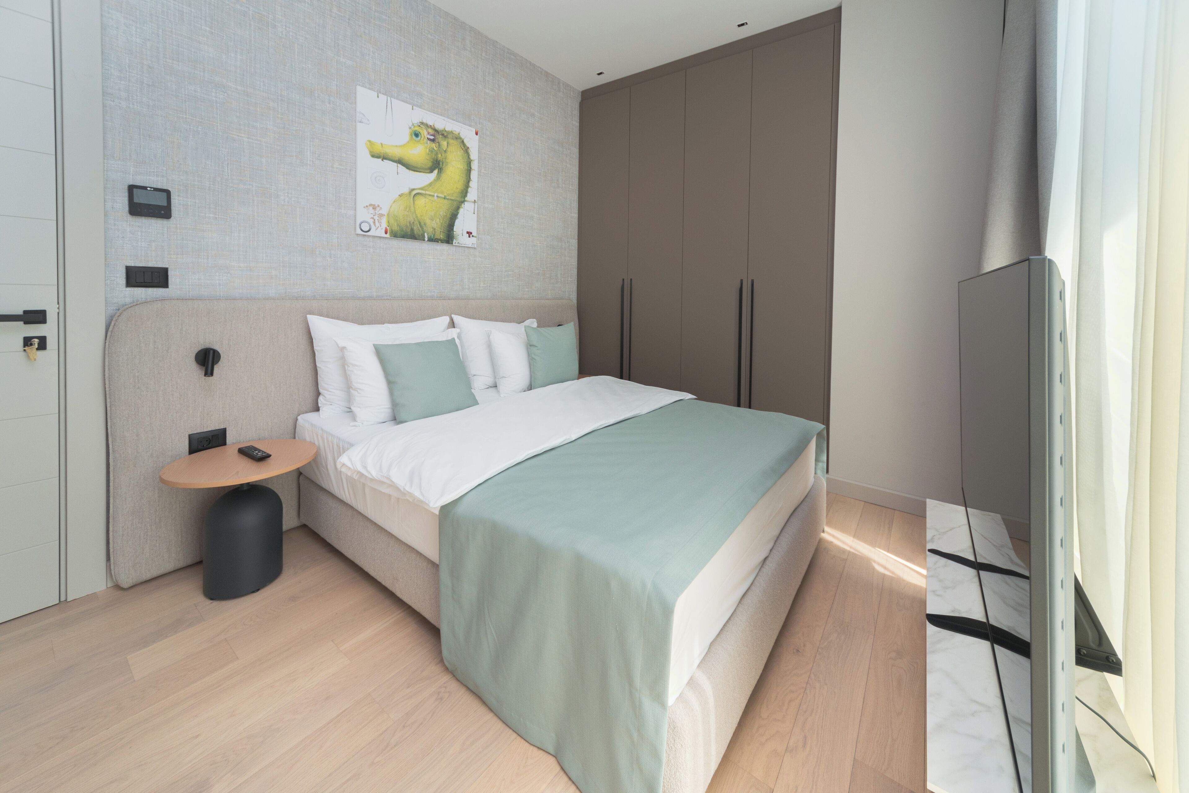 A modern bedroom with a bed, bedside table, and a mounted TV.