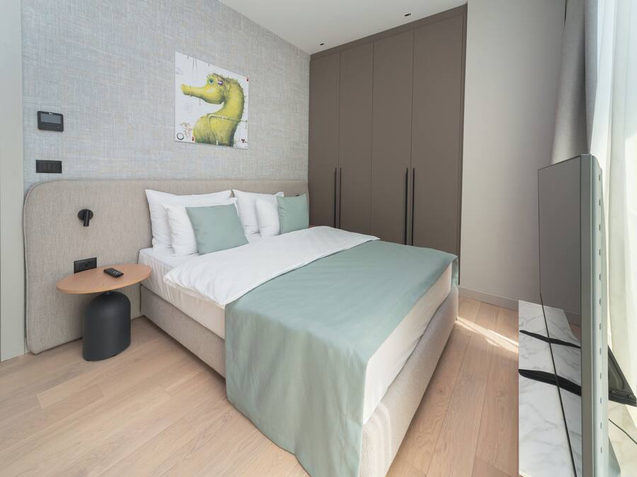 A modern bedroom with a bed, bedside table, and a mounted TV.