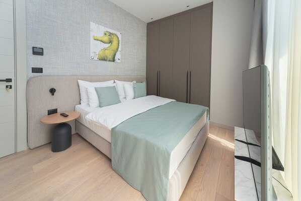 Un dormitorio moderno con cama, mesita de noche y televisor montado.