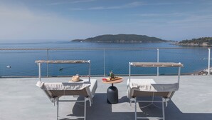 A terrace with two chairs and a table, overlooking a calm sea and a distant island. - Sea Star Budva (Becici)