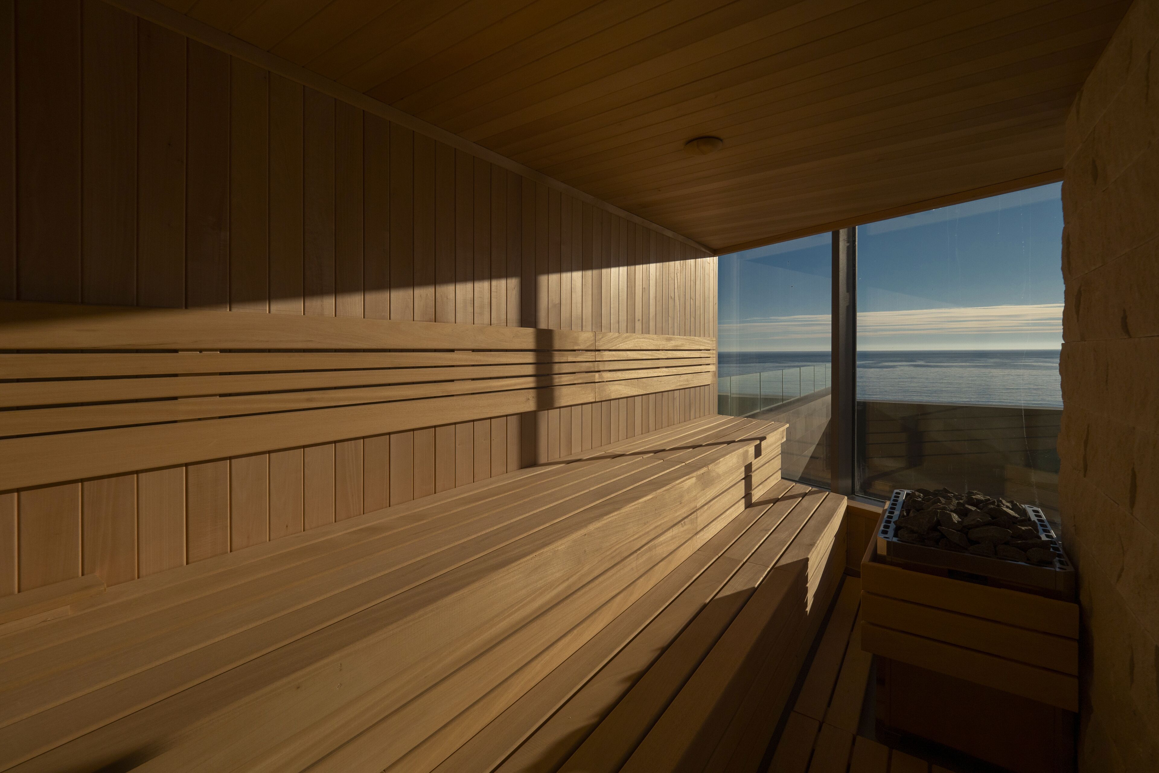 Una sauna con bancos de madera y un amplio ventanal con vistas al cielo.