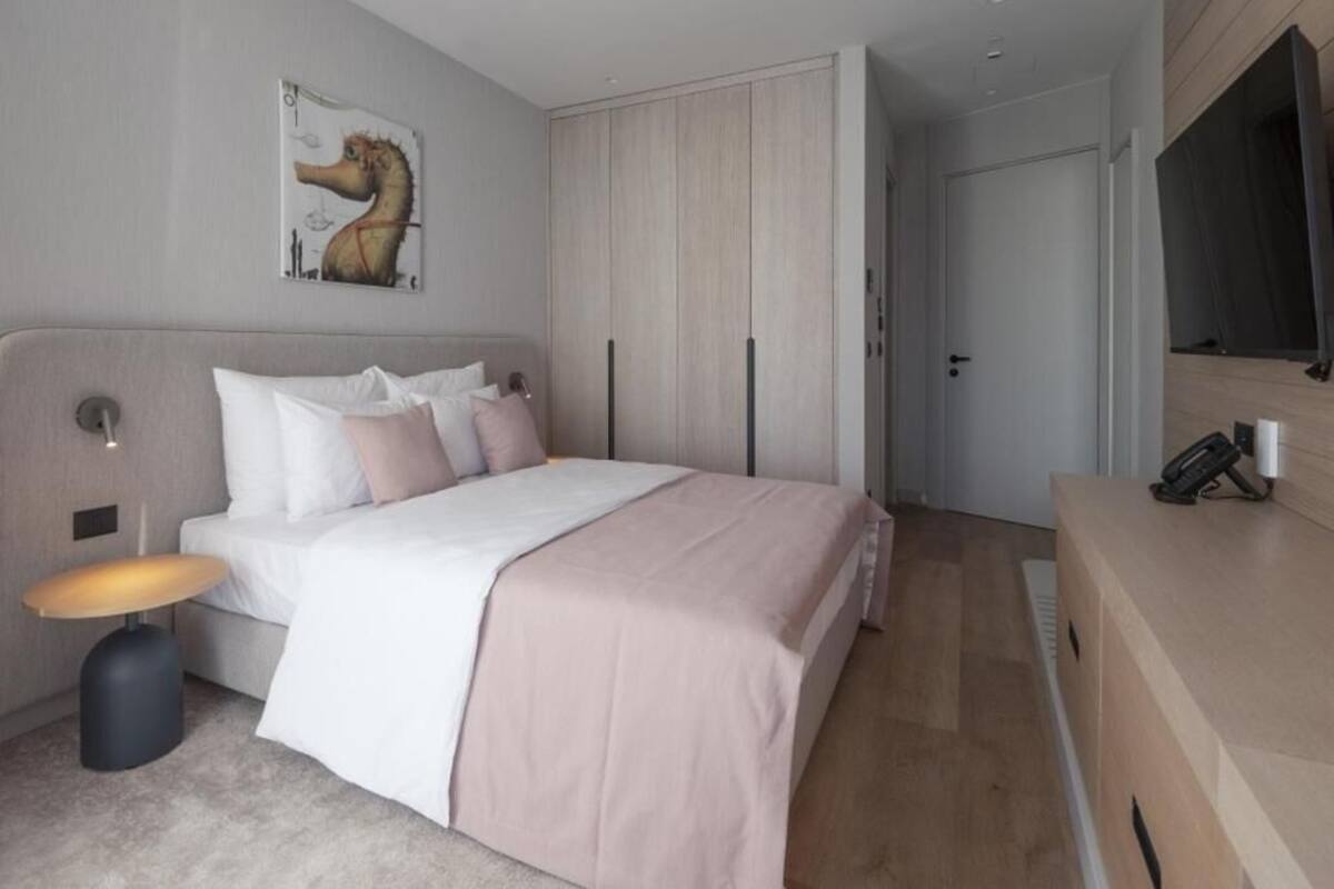 A modern bedroom with a bed, bedside table, wardrobe, and a painting on the wall.