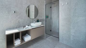 A modern bathroom with a large sink, mirror, and glass shower enclosure.