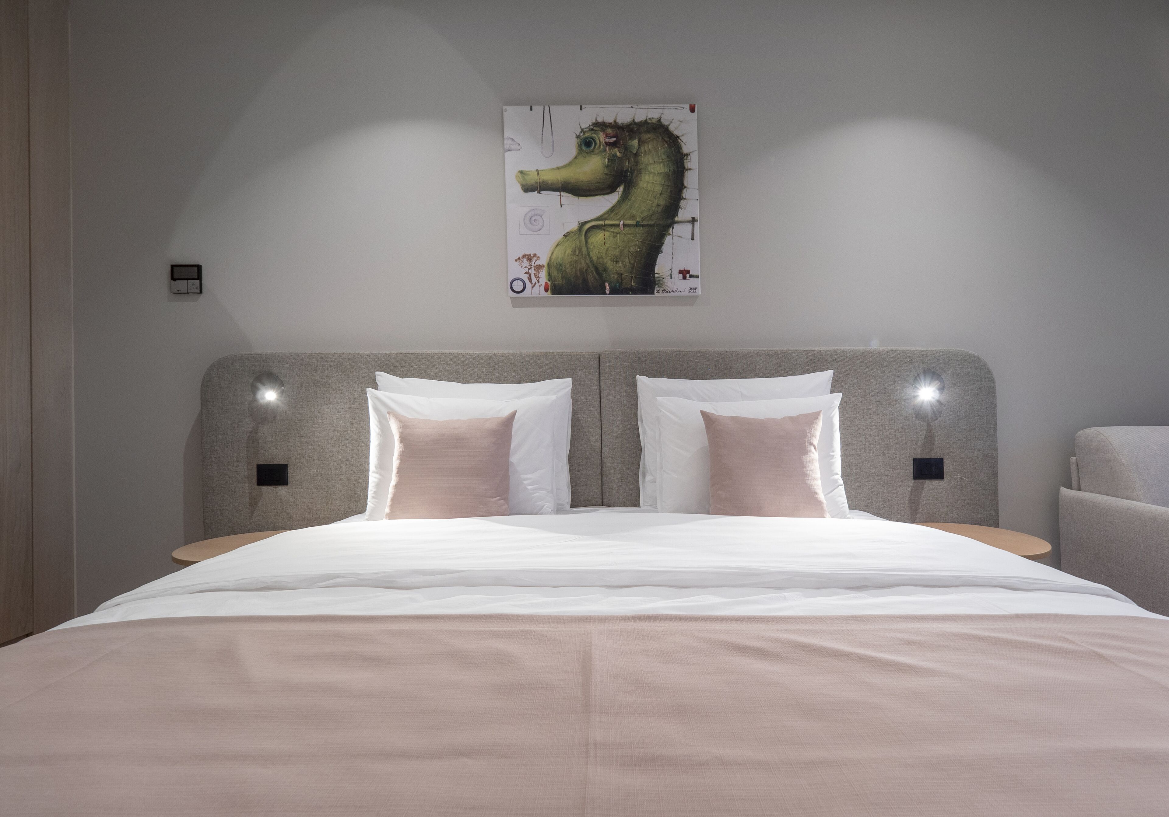 A modern bedroom with a large bed, two bedside tables, and a unique seahorse artwork on the wall.