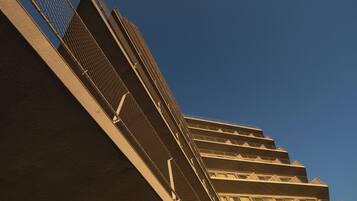 A multi-story building with a series of balconies and a metal railing.