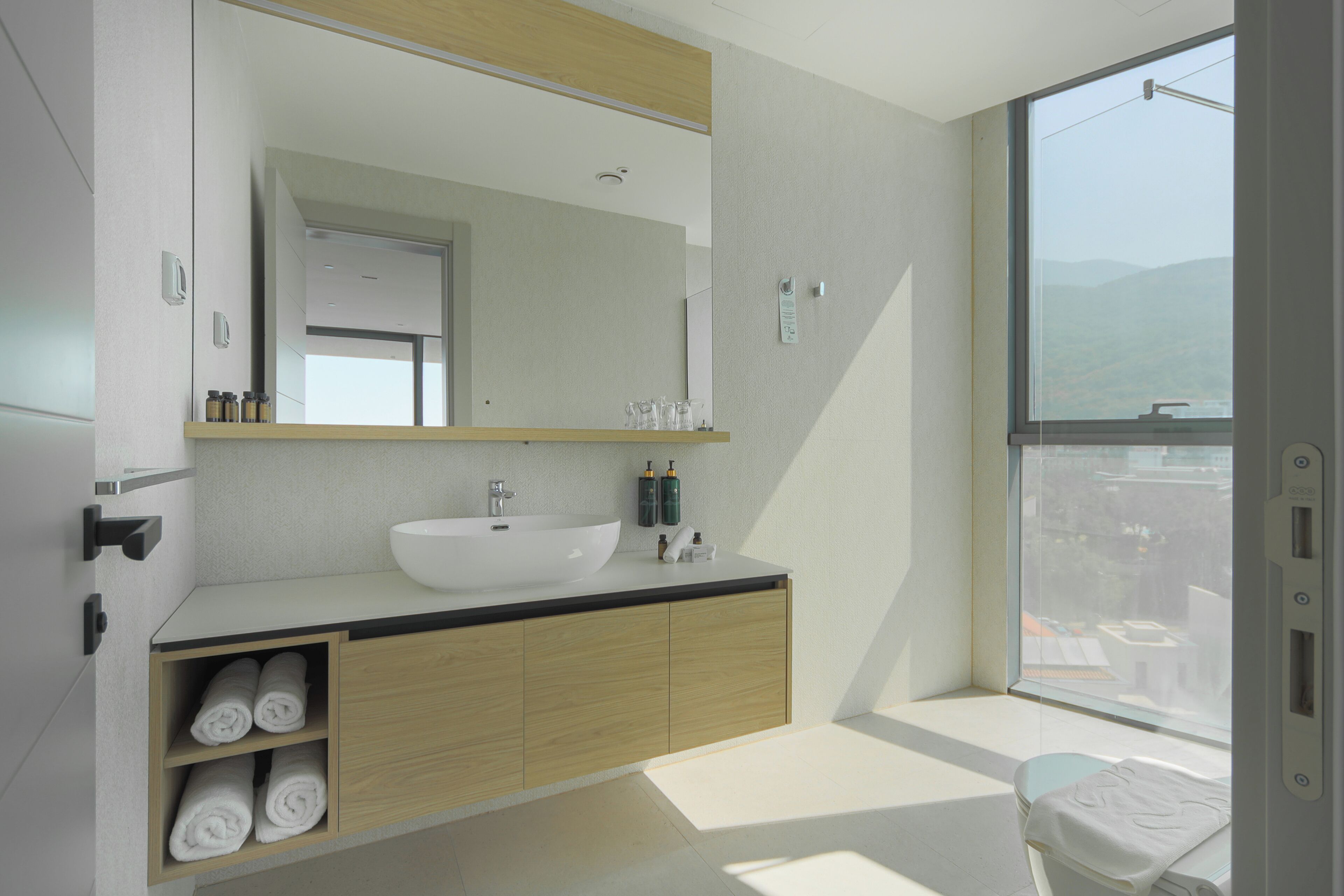 Een moderne badkamer met een groot wastafel, spiegel en raam.