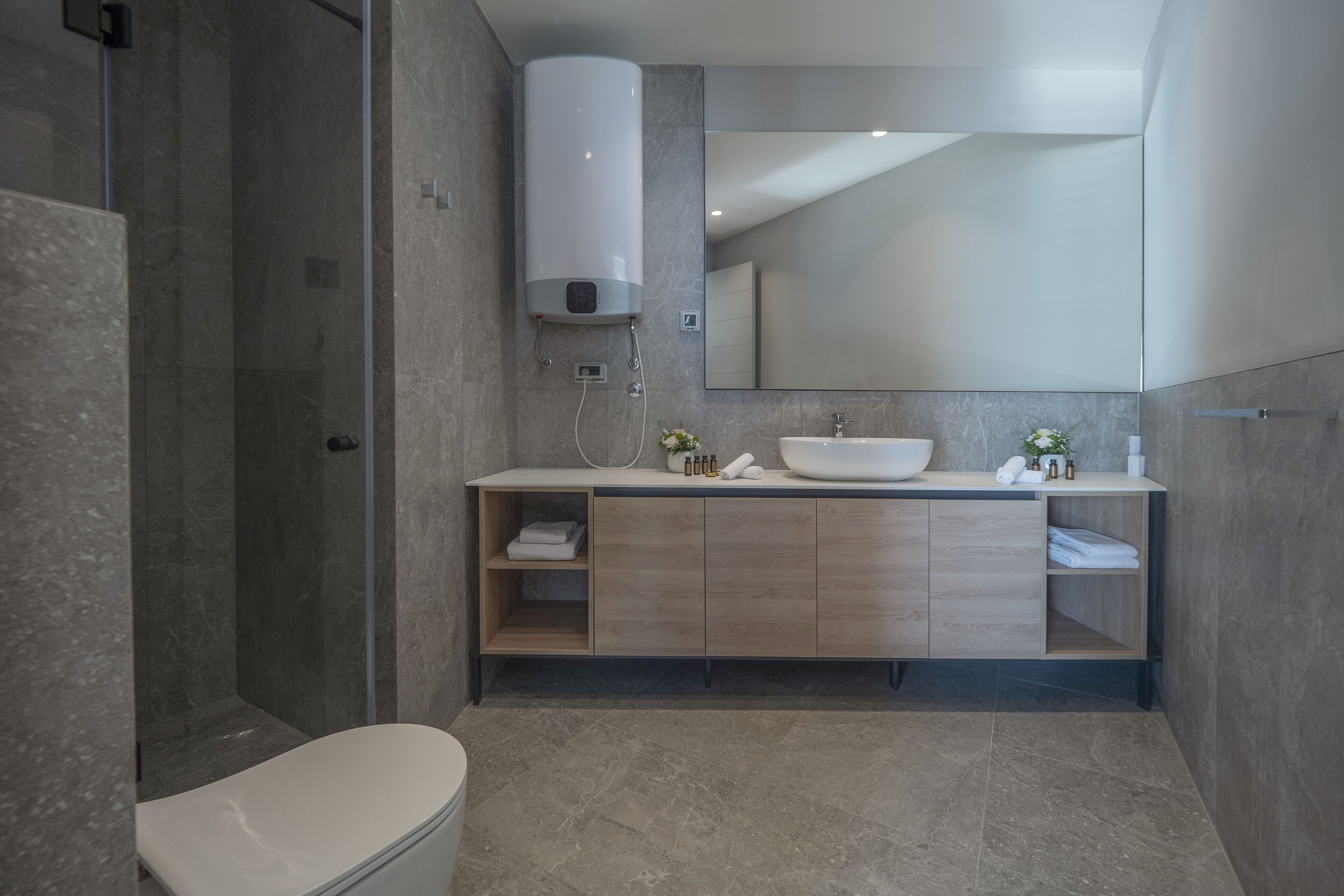 Un baño moderno con ducha, inodoro y tocador con lavabo y espejo.