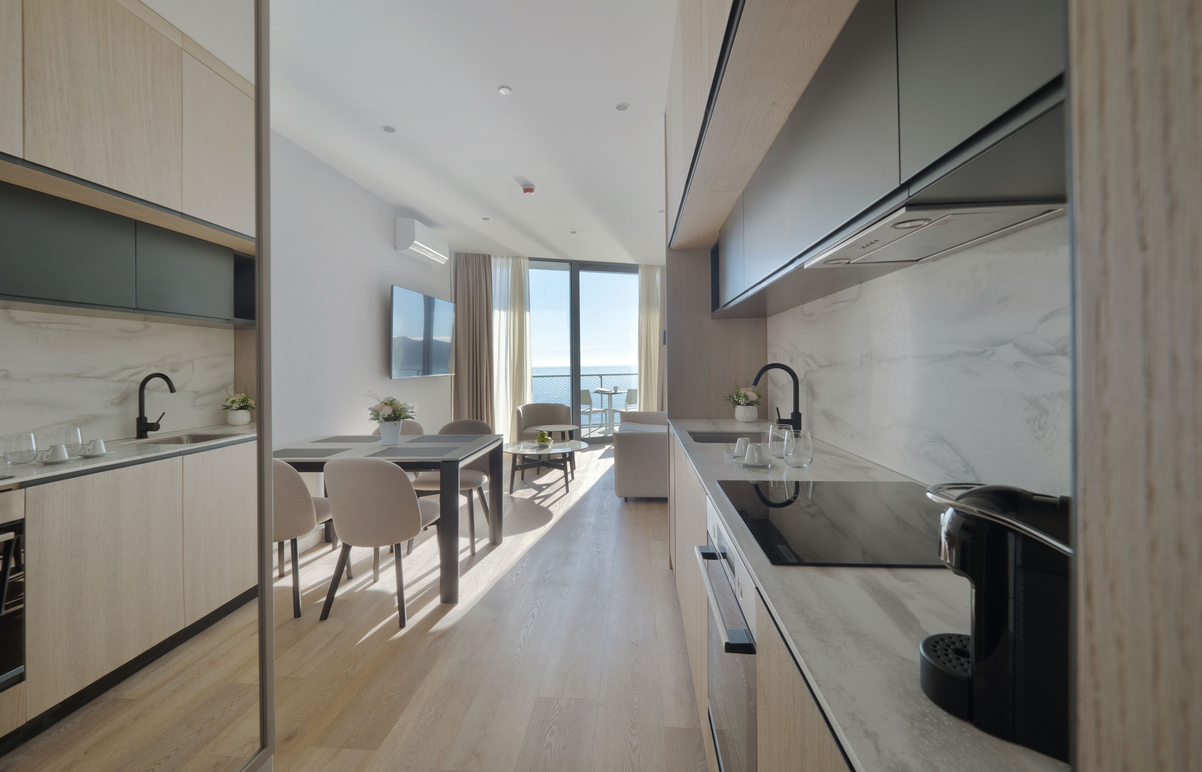 A modern kitchen with a central island, a dining area with a view, and a large window.