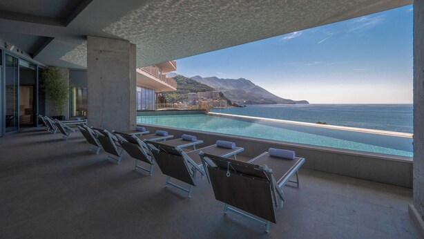 A poolside area with lounge chairs and a view of the ocean. - Sea Star Budva (Becici)