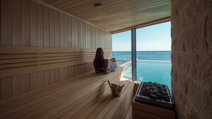 A sauna with wooden benches, a view of the ocean, and a stone wall. - Sea Star Budva (Becici)