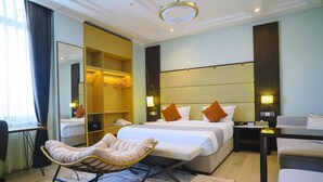 Una habitación de hotel moderna con una cama grande, una zona de estar, un armario y un espejo.