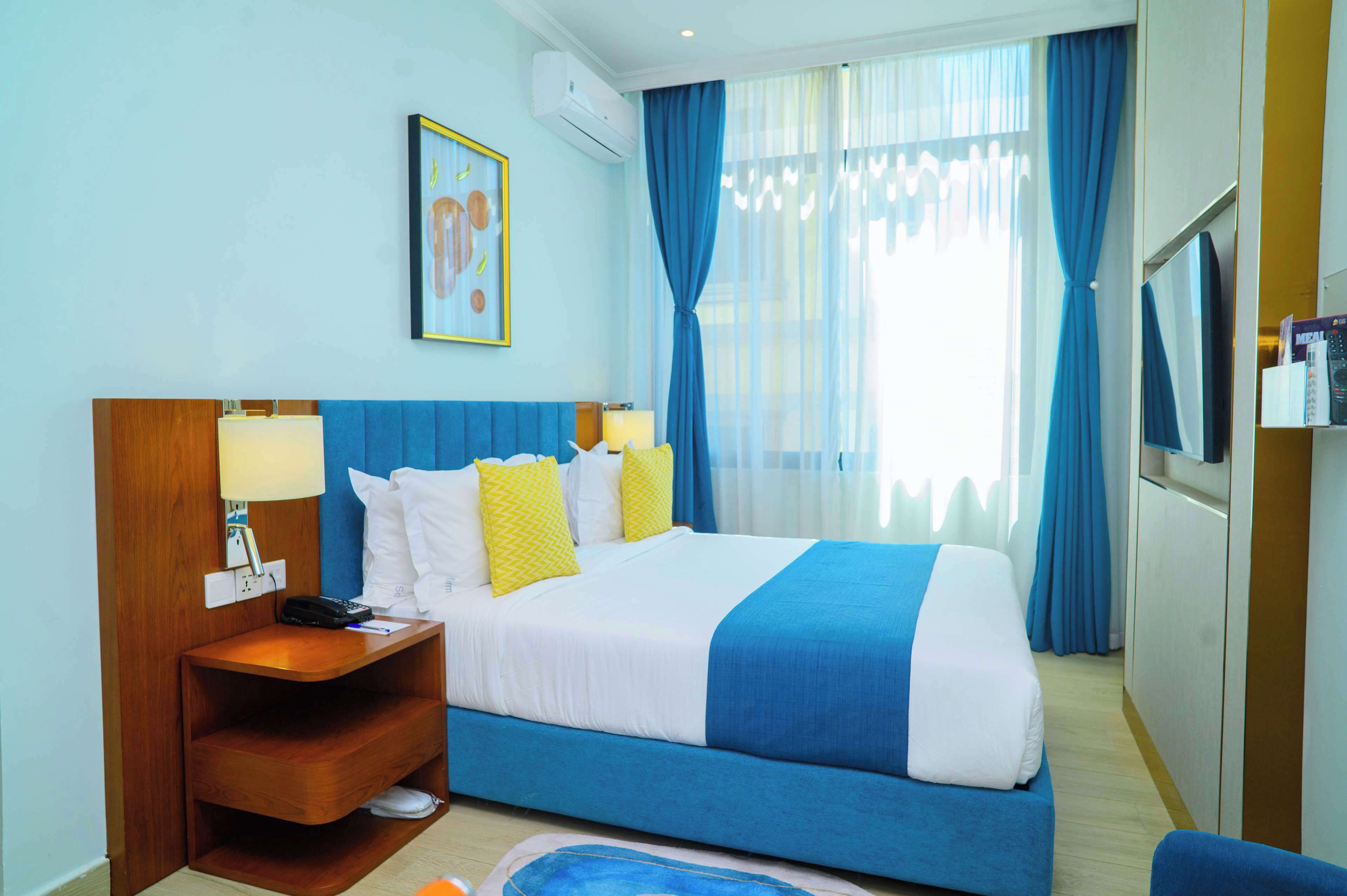 A hotel room with a bed, bedside table, lamp, and a television.