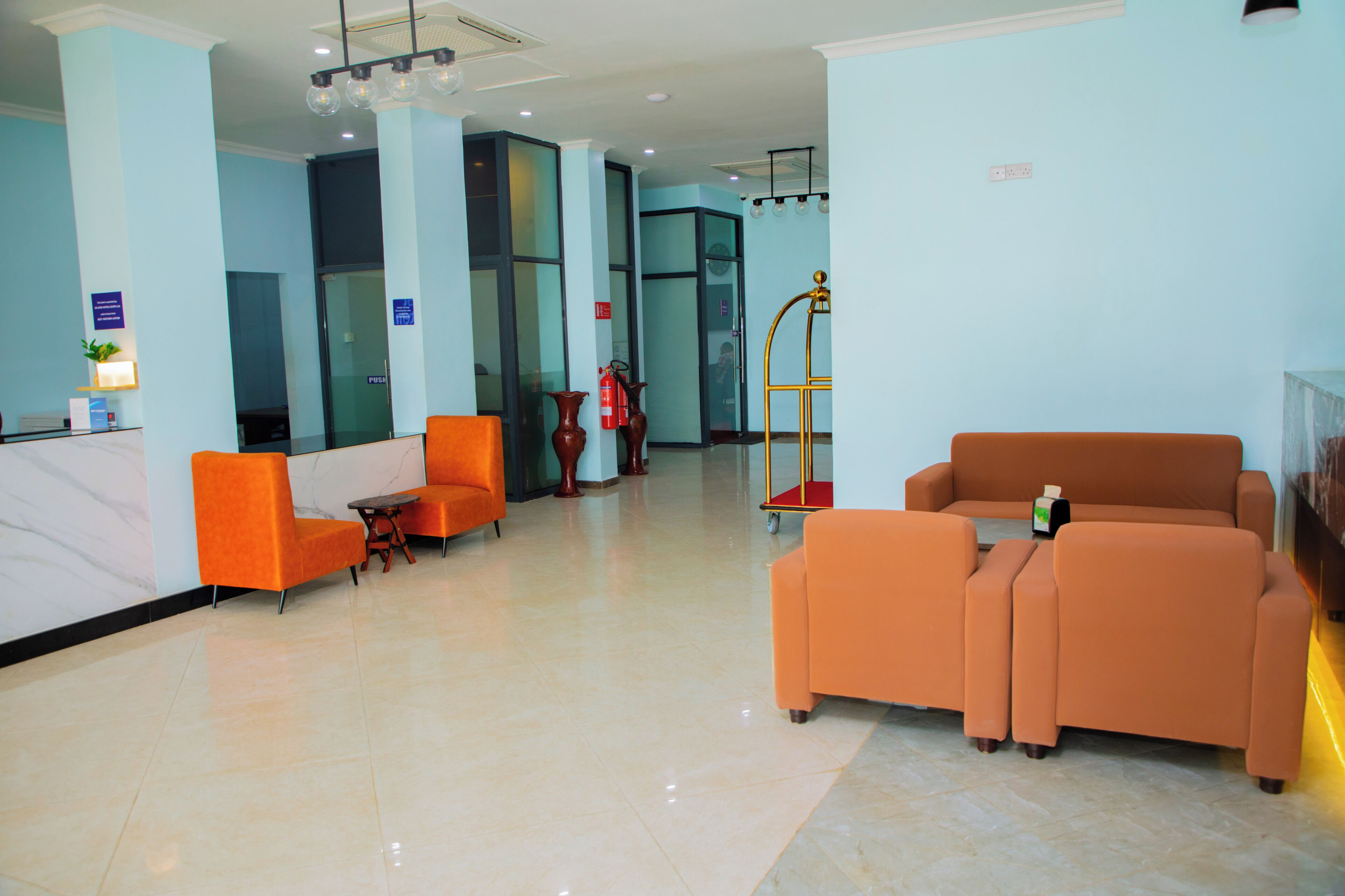 A lobby with orange seating, a reception desk, and a fire extinguisher.
