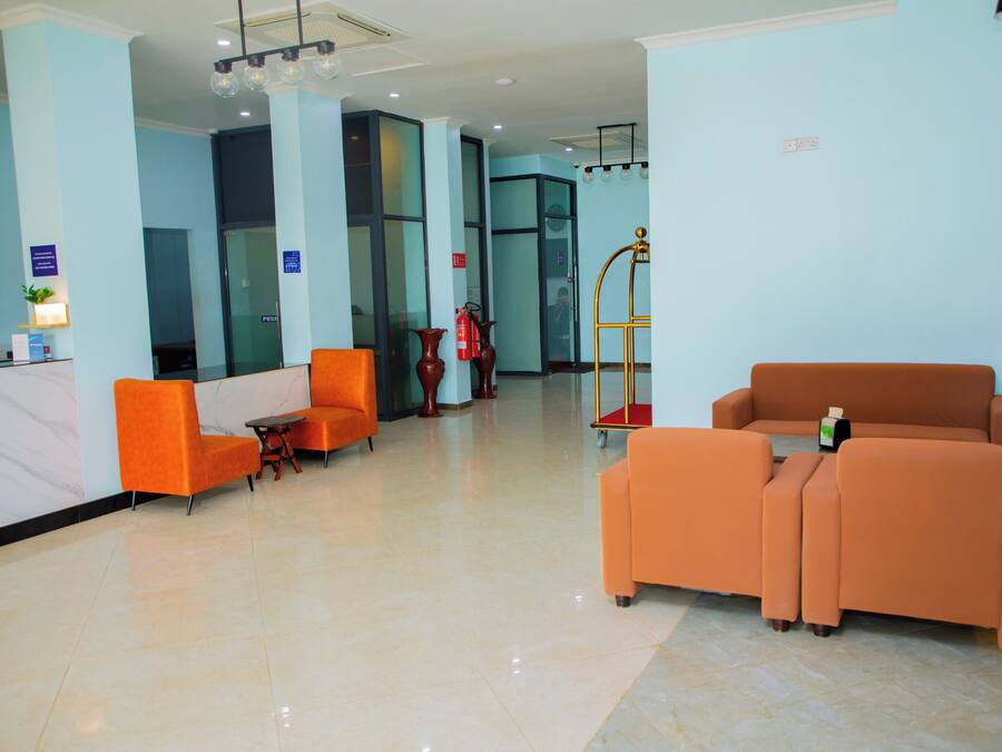 A lobby with orange seating, a reception desk, and a fire extinguisher.