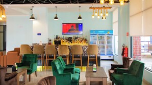 Zona de bar con diversas opciones de asientos, una pantalla de televisión y una variedad de botellas en la barra.