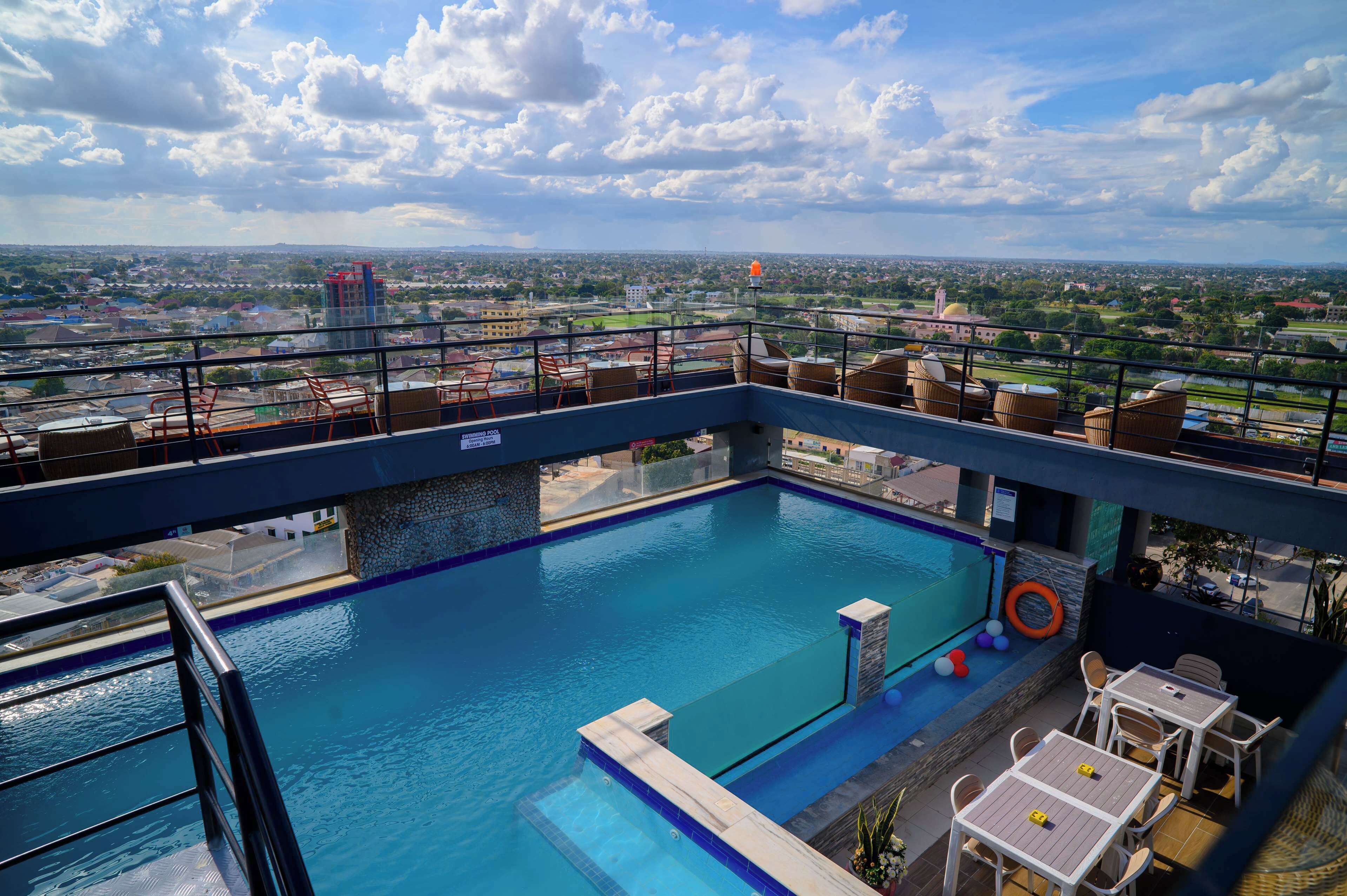 A rooftop pool with a view of the cityscape, including buildings and a distant tower.
