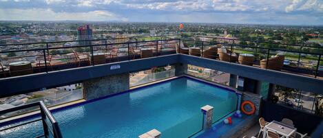 A rooftop pool with a view of the cityscape, including buildings and a distant tower.