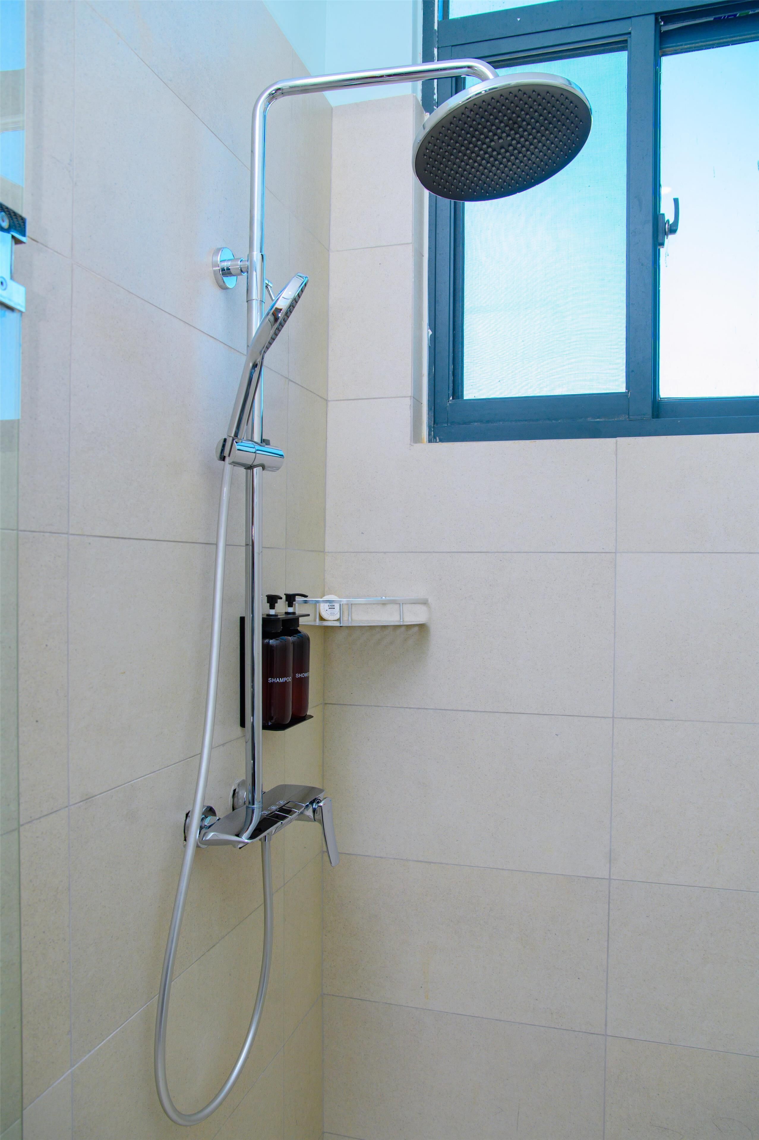A shower with a handheld showerhead and a wall-mounted faucet.