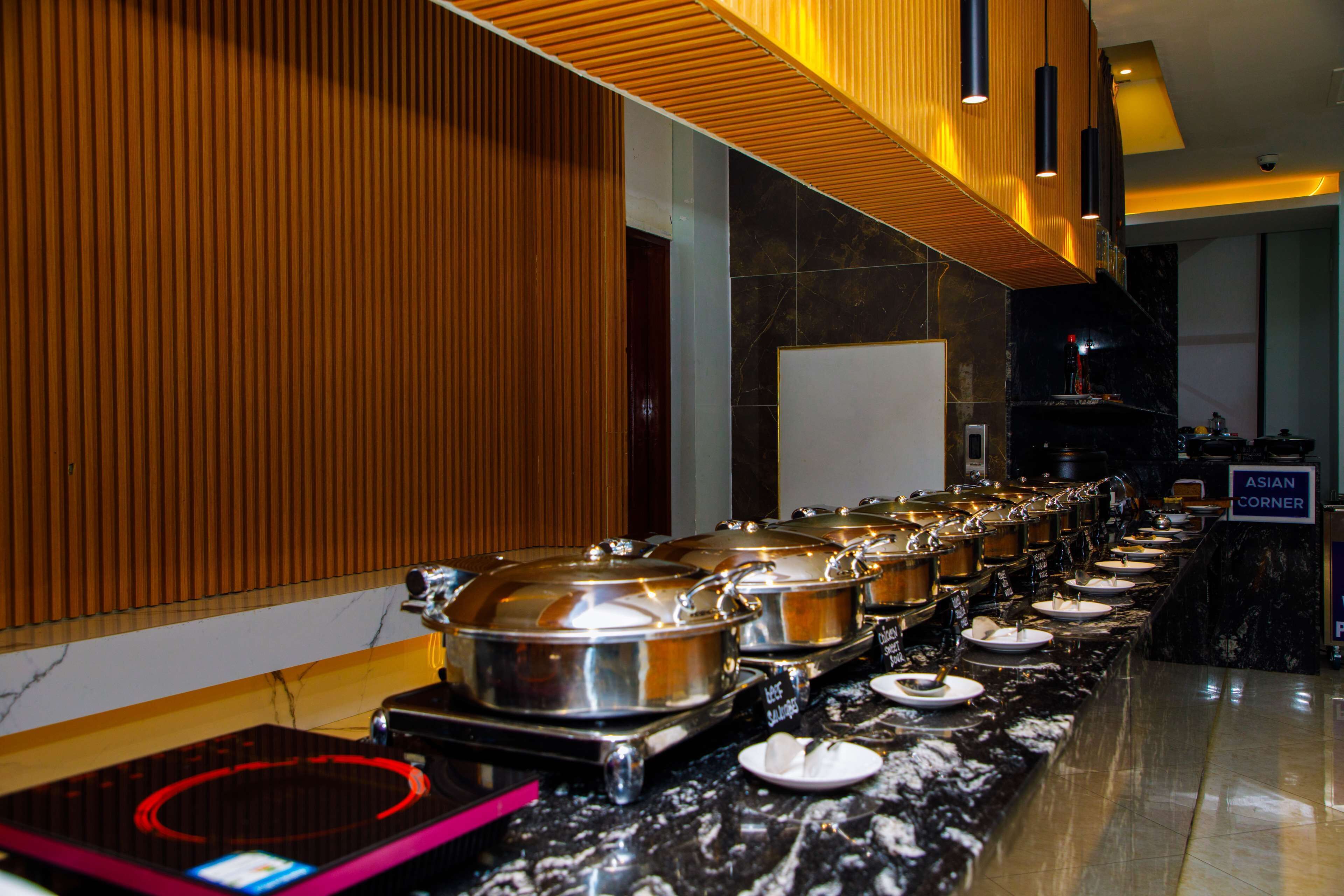 A buffet setup with multiple serving stations, a wooden panel wall, and a marble countertop.