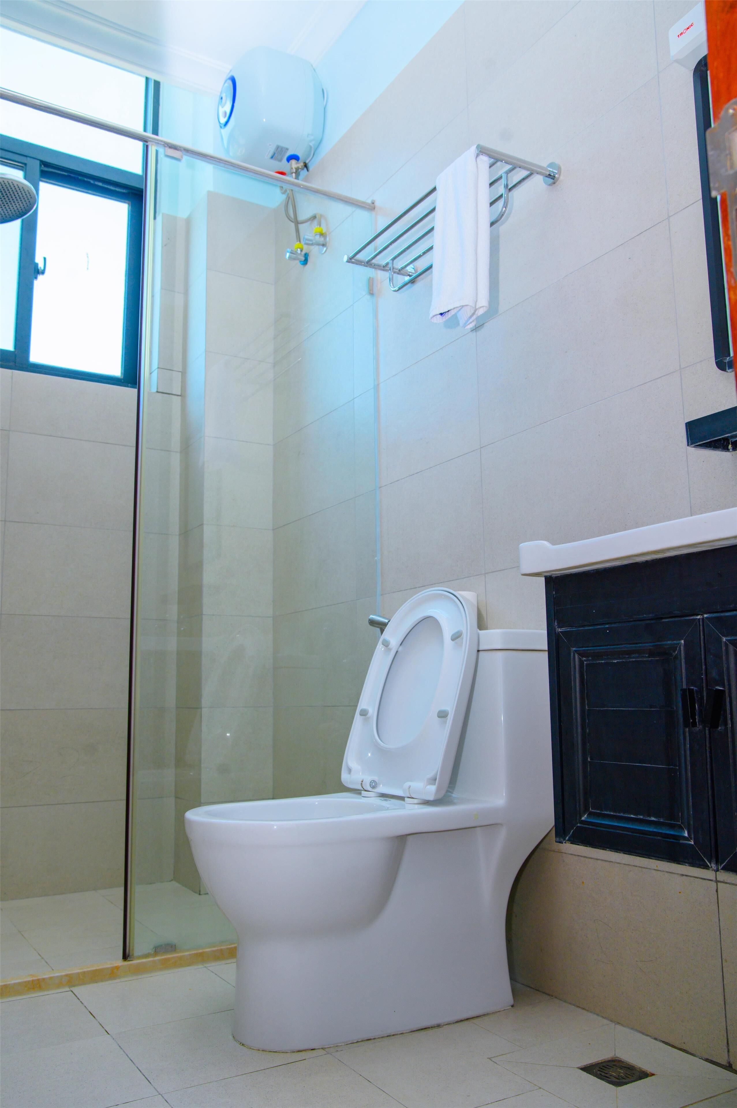 Un baño con inodoro blanco, cabina de ducha de vidrio y perchero para toallas.