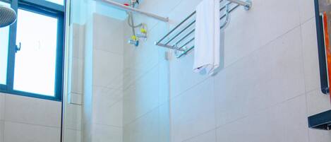Un baño con inodoro blanco, cabina de ducha de vidrio y perchero para toallas.