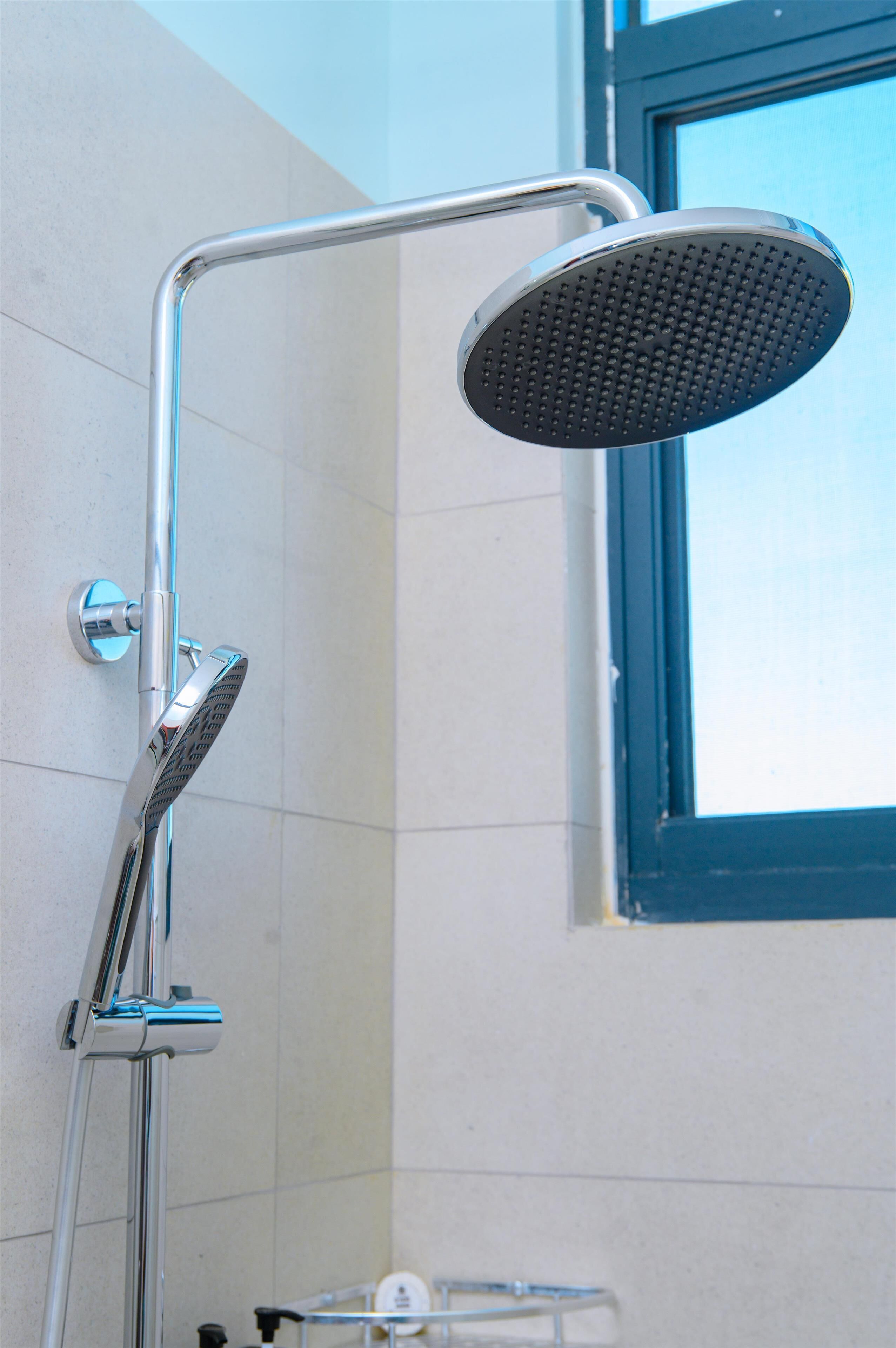 A shower with a handheld showerhead and a wall-mounted control.