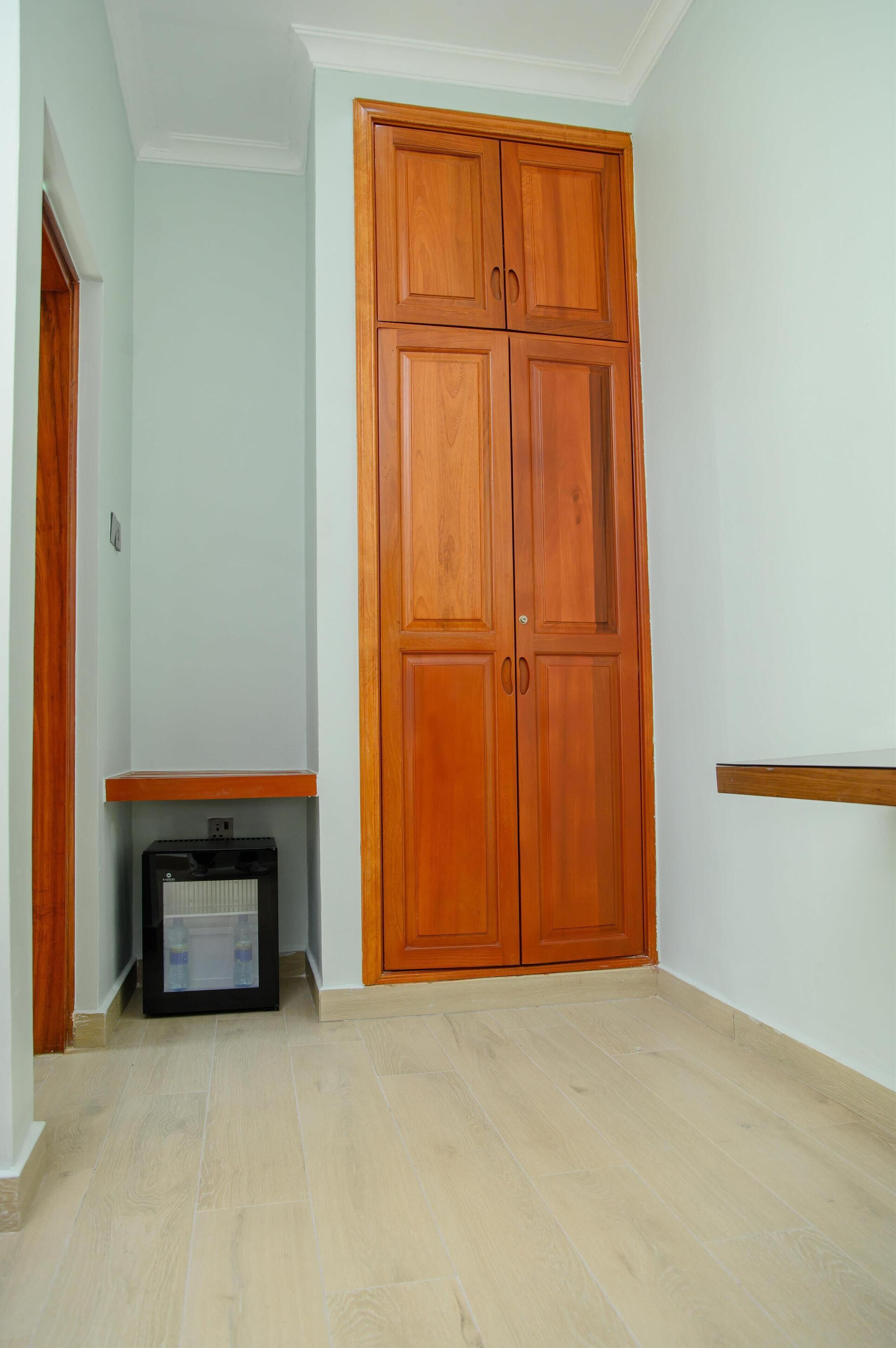 Una habitación con un armario de madera, un espacio reducido con radiador y un suelo de baldosas claras.