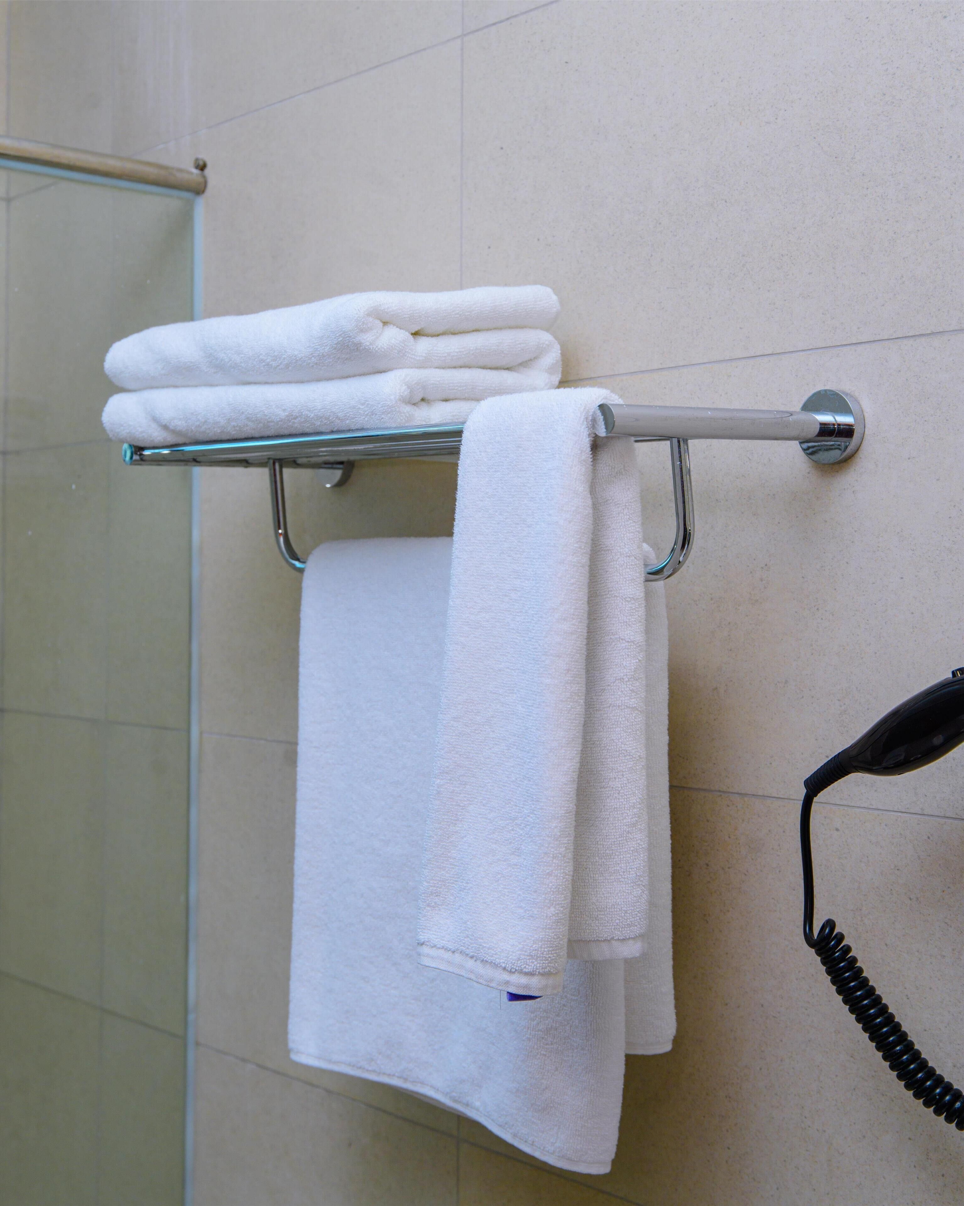A bathroom with a towel rack holding folded towels and a telephone.