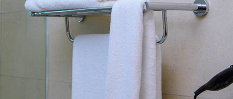 A bathroom with a towel rack holding folded towels and a telephone.