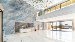 A spacious lobby with marble flooring, a reception desk, and a large glass window offering a view of the outdoors. - Grand Elis Hotel  (Ilida)