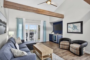 A living room with a sofa, chairs, a coffee table, and a kitchen area with a counter and cabinets. - Bridgepointe Condo - Two Bedroom Apartment, Sleeps 6 (Osage Beach)