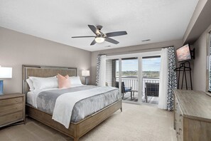A bedroom with a bed, a ceiling fan, a TV, a balcony with a view, and a desk. - Bridgepointe Condo - Two Bedroom Apartment, Sleeps 6 (Osage Beach)