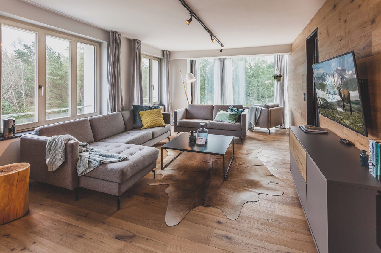 En moderne stue med sofa, sofabord og fjernsyn på en trævæg.
