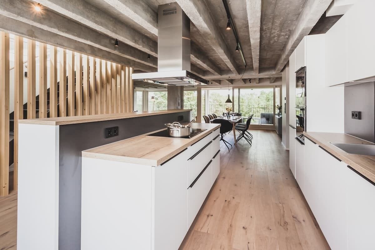 Eine moderne Küche mit Holzelementen, ein Essbereich mit Aussicht und ein großzügiges Layout.