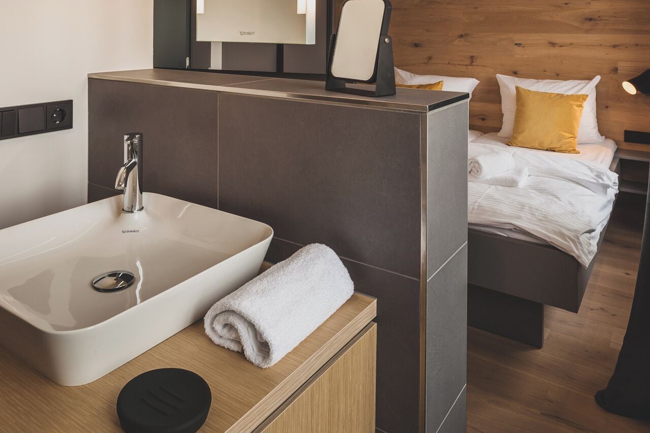 Une salle de bain moderne avec un grand lavabo, un miroir et une serviette posée sur le comptoir.