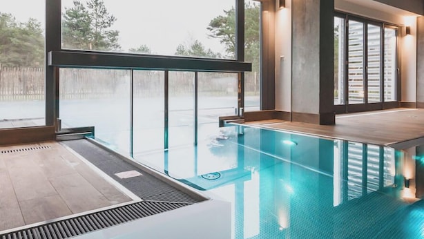 A modern indoor swimming pool with large windows and a view of the outdoors. - Mariandl am Meer (Binz)