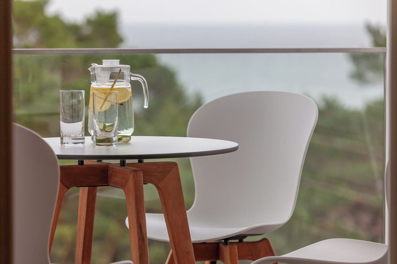 Ein Tisch mit einer Wasserkaraffe und einem Glas, mit Blick auf das Meer.