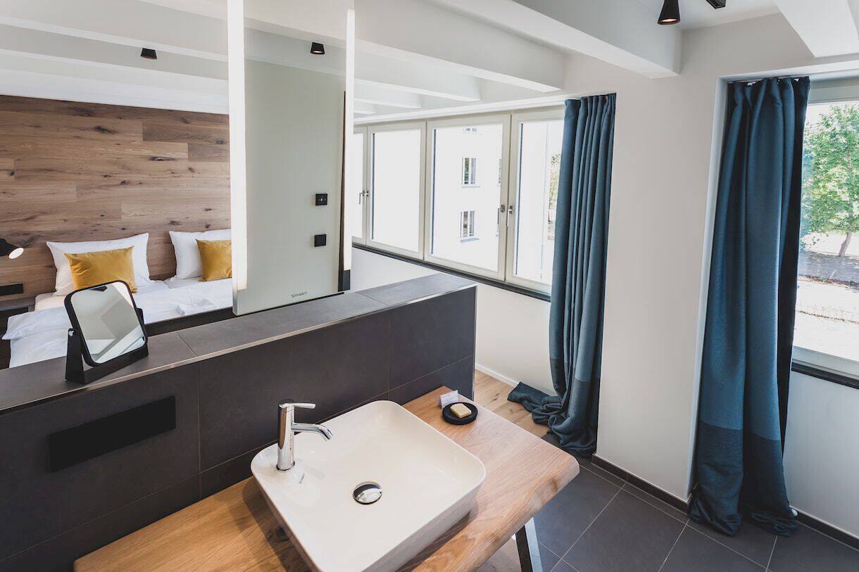 A modern bathroom with a wooden vanity, a large mirror, and a sink.