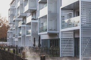 Un edificio moderno con varios balcones, algunos con barandillas de vidrio y otros de metal.