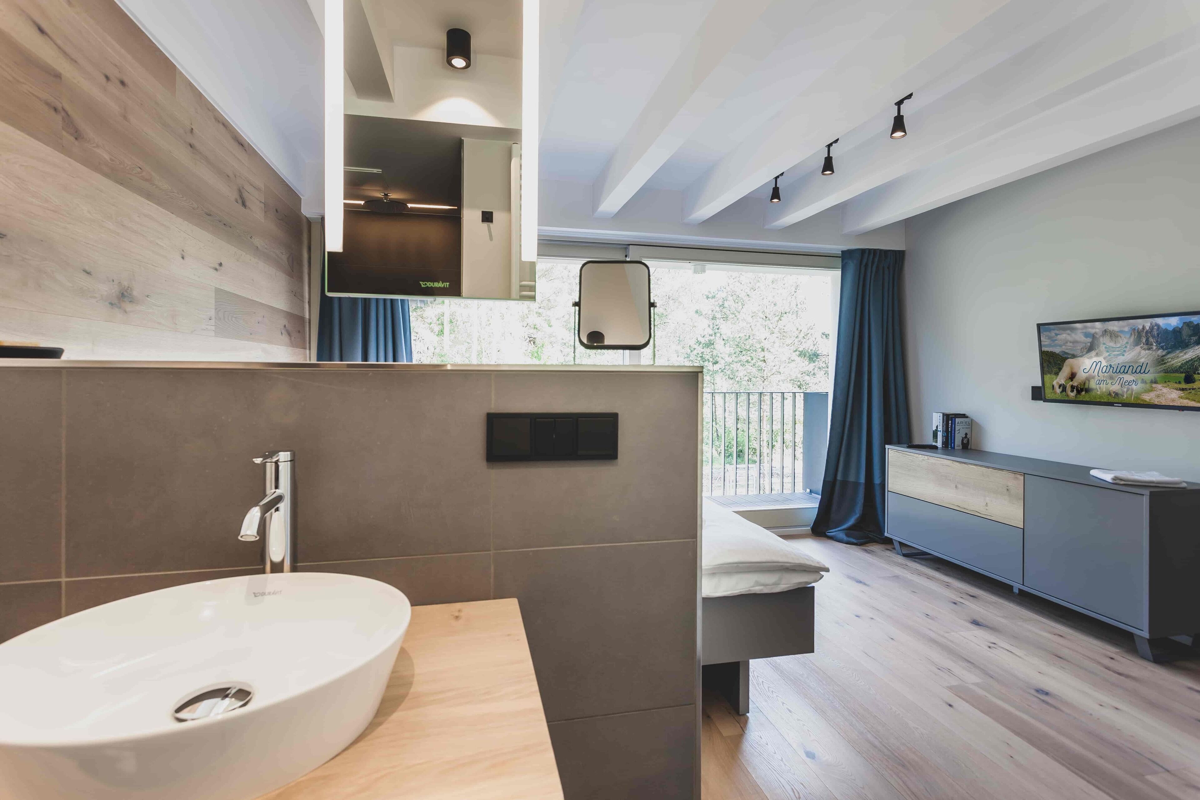 Un baño moderno con un lavamanos ovalado grande, un espejo y un mueble de tocador de madera.