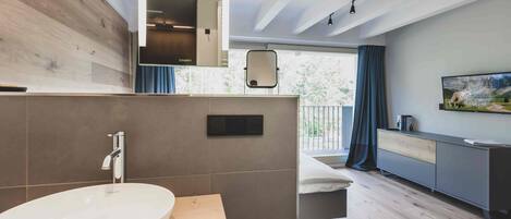 Un baño moderno con un lavamanos ovalado grande, un espejo y un mueble de tocador de madera.