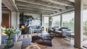 A modern living room with a fireplace, sofas, and a large window overlooking a balcony. - Mariandl am Meer (Binz)