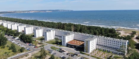 Um complexo moderno de hotel com vários edifícios, um estacionamento e vista para o mar.