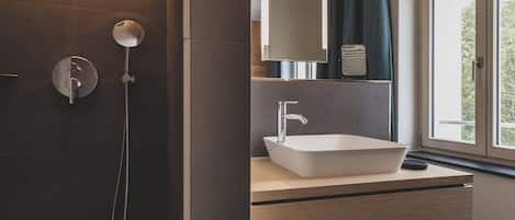 A modern bathroom with a large window, a white sink, and a shower area.